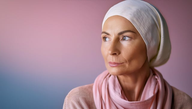 A woman with a serene expression wears a light pink scarf and a white head covering, looking to the side. Her skin is smooth, and her eyes are bright and focused.