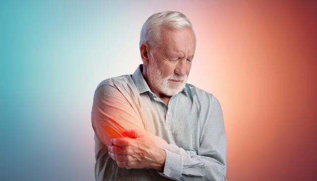 An older man clutches his painful right elbow with his left hand, grimacing, with a glowing red spot indicating the pain's location. He wears a light checkered shirt