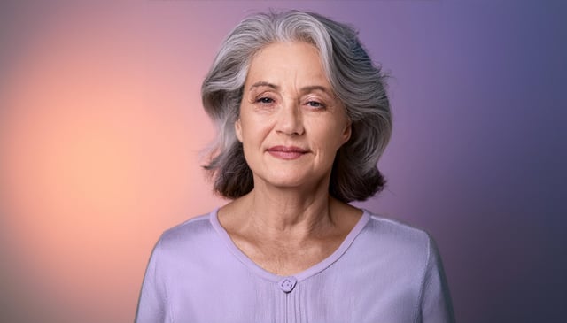 An elderly hispanic woman with white hair and wearing a light purple shirt. Her face shows wrinkles, highlighting her kind expression. One eye is drooping slightly.